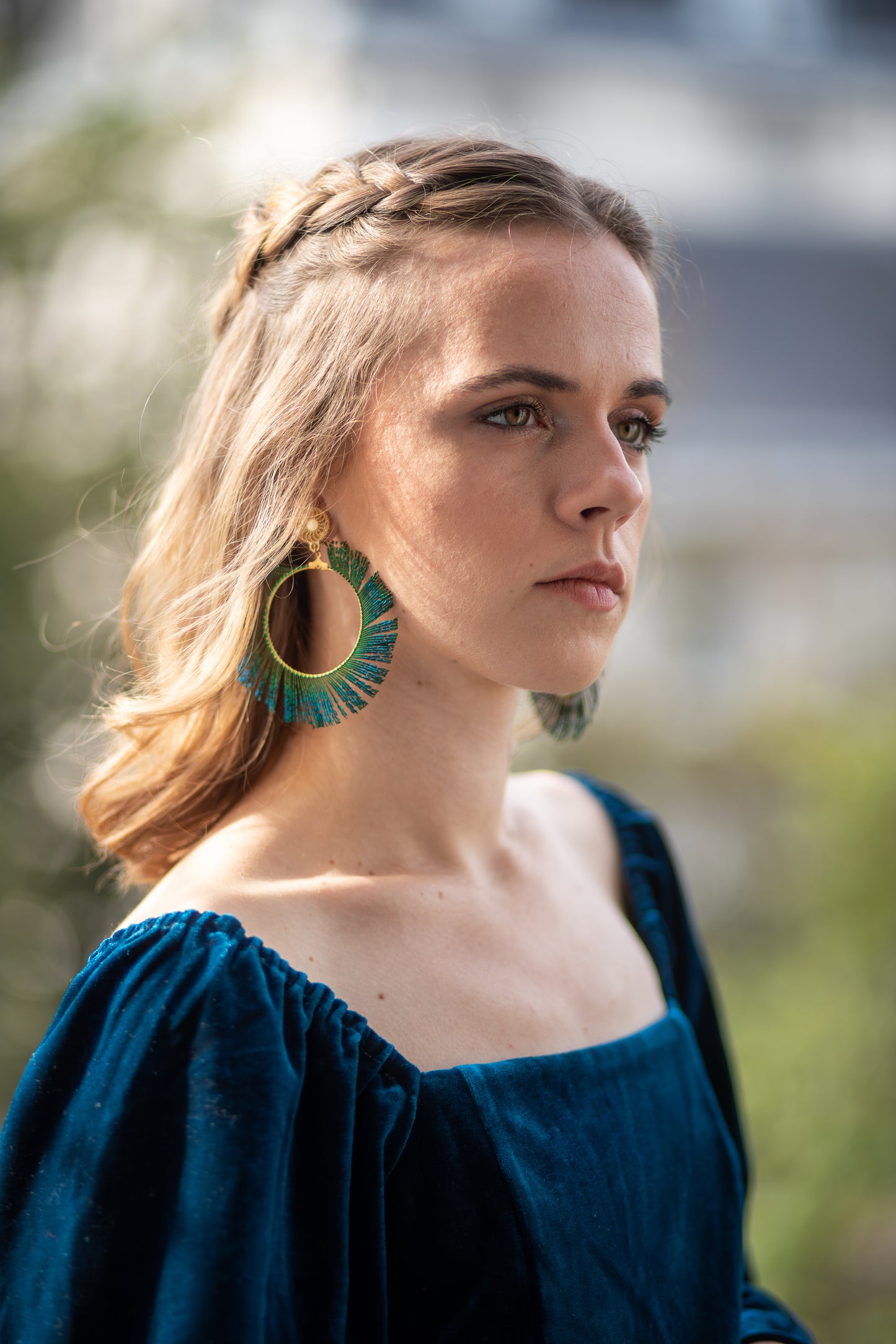 Boucles d’oreilles ornées d’une plume de paon autour d’une créole, personnalisables pour oreilles percées ou à clips.