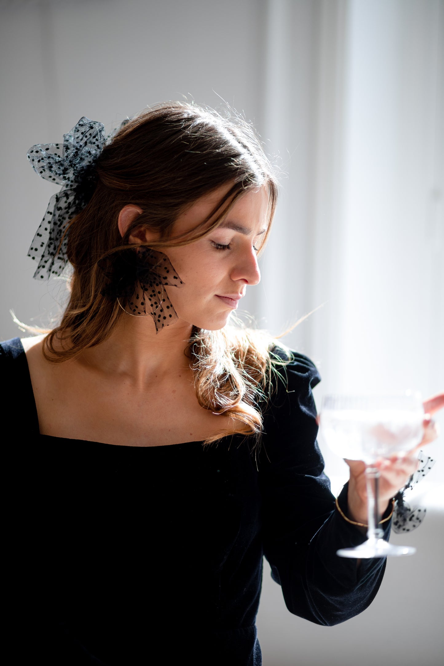 Boucles d’oreilles ornées d’un noeud en plumetis noir autour d’une créole, personnalisables pour oreilles percées ou à clips.