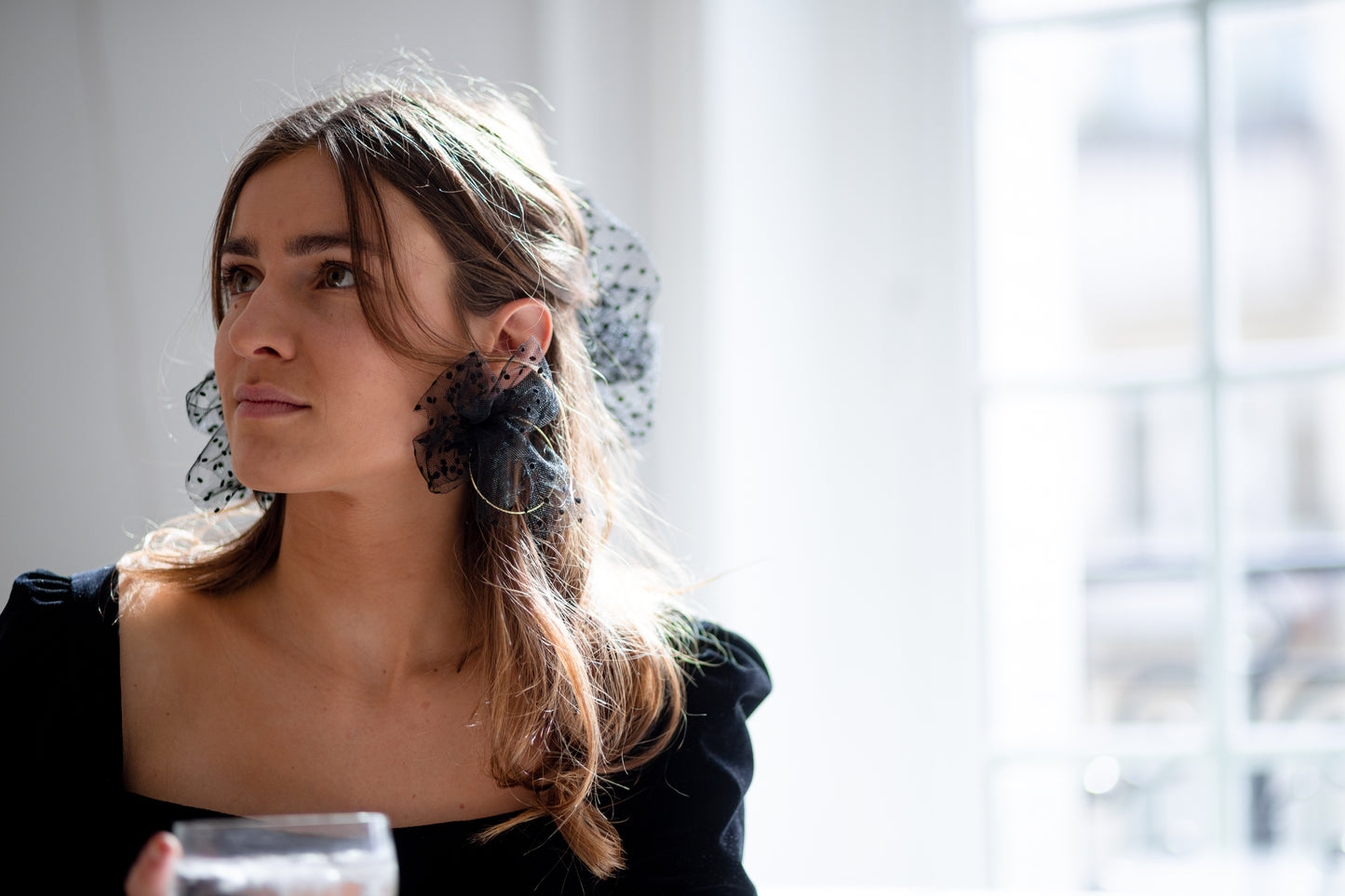 Boucles d’oreilles ornées d’un noeud en plumetis noir autour d’une créole, personnalisables pour oreilles percées ou à clips.