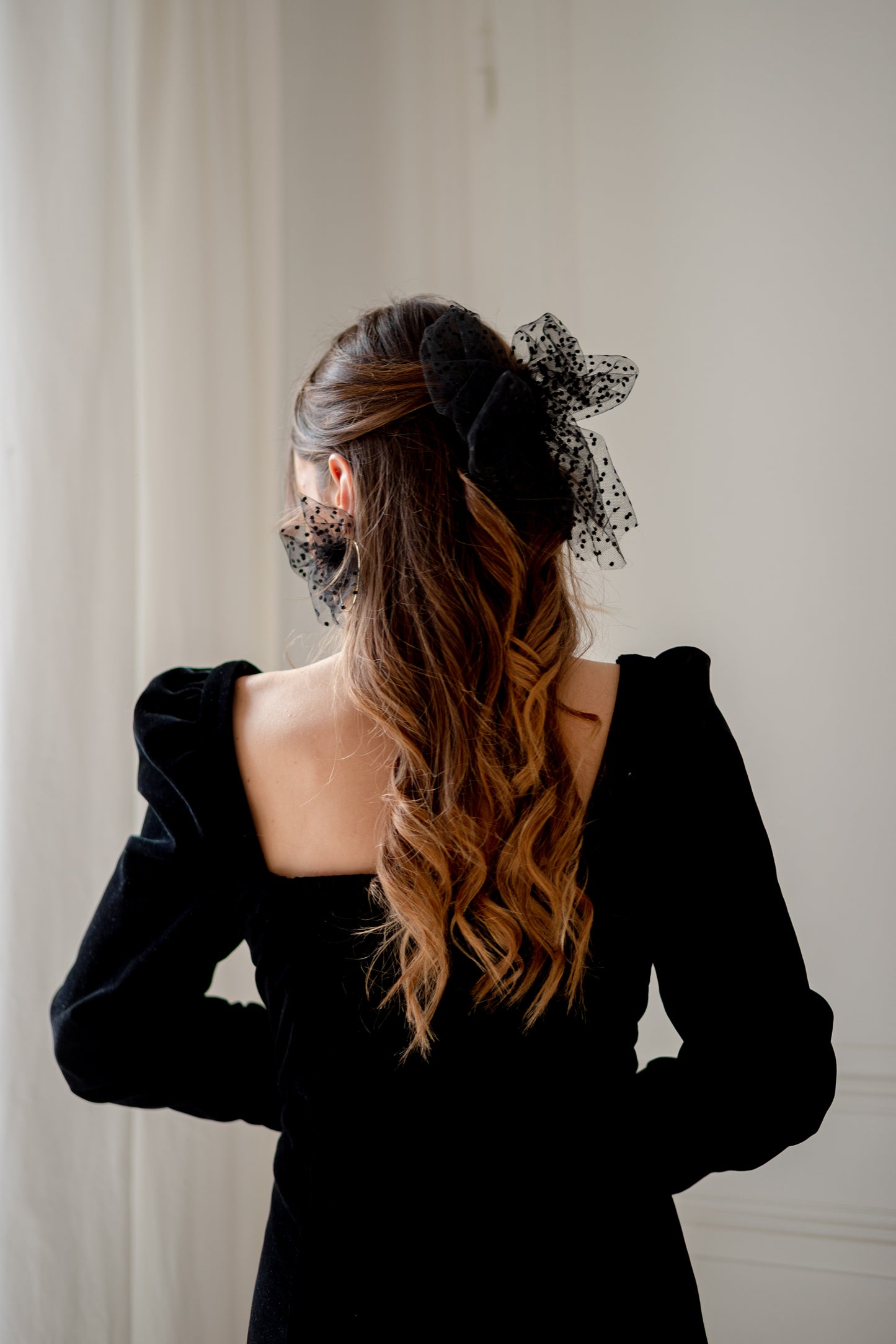 Boucles d’oreilles ornées d’un noeud en plumetis noir autour d’une créole, personnalisables pour oreilles percées ou à clips.