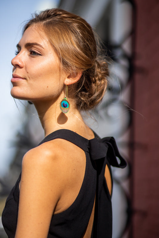 Boucles d'oreilles avec une chaîne dorée à l'Or fin garnie d'une plume de paon, personnalisables pour oreilles percées ou à clips.