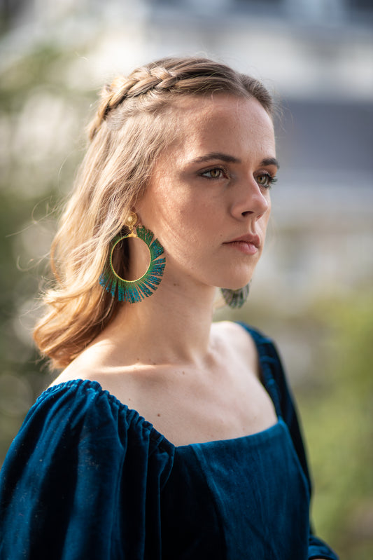 Boucles d’oreilles ornées d’une plume de paon autour d’une créole, personnalisables pour oreilles percées ou à clips.