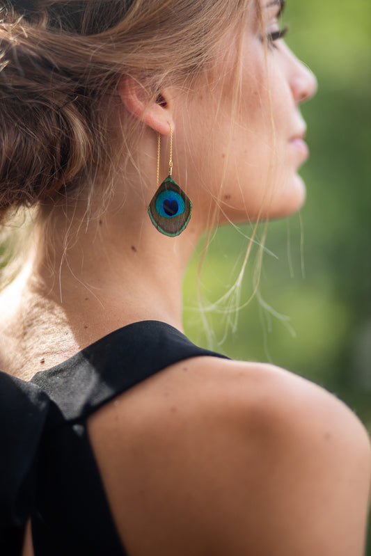 Boucles d'oreilles avec une chaîne dorée à l'Or fin garnie d'une plume de paon, personnalisables pour oreilles percées ou à clips. 
